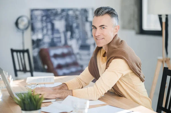 Ένας άντρας με καθημερινά ρούχα κάθεται στο τραπέζι στο γραφείο. — Φωτογραφία Αρχείου