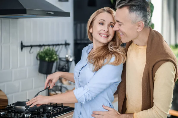 Pár objetí v kuchyni a vypadá šťastně — Stock fotografie