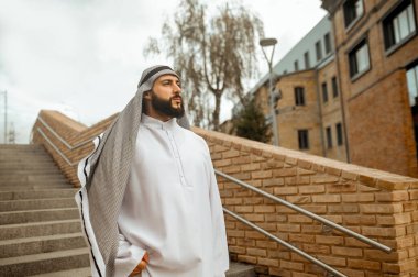 Beyaz giysili Arap bir adam merdivenlerde.