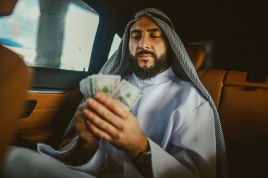 Elinde para olan geleneksel giysili Arap bir adam.