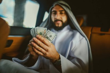 Elinde para olan geleneksel giysili Arap bir adam.