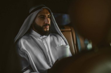 Geleneksel Arap kıyafetli bir adam arabada.