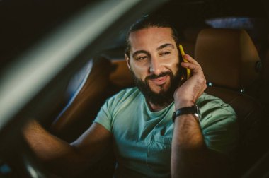 Elinde telefon olan yakışıklı, koyu renk saçlı bir adam.