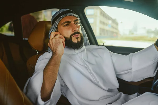 Saudi man sitting in a car and talking on the phone