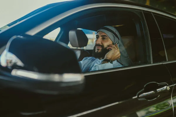 Hombre saudí sentado en un coche y hablando por teléfono — Foto de Stock