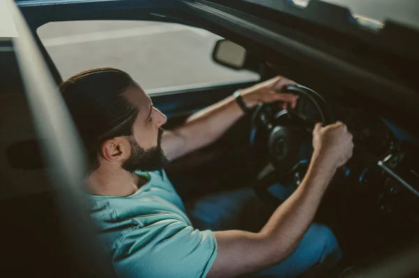 Joven hombre guapo de pelo oscuro conduciendo un coche — Foto de Stock