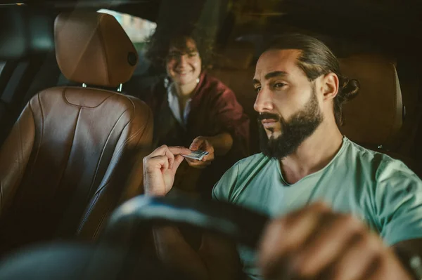 Un joven conductor con barba en un coche con una clienta — Foto de Stock