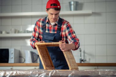 Tulum ve kep giymiş konsantre olmuş genç marangozlar saman kutusunun kenarlarını birleştiriyor.