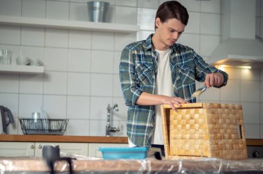 Sakin, ekose gömlekli genç adam ahşap kutunun üzerinde fırçayı tutuyor.