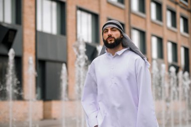 Ofis bölgesinde. Sokakta yürüyen geleneksel giysili Ortadoğulu genç adam.