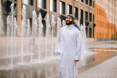 Ofis bölgesinde. Sokakta yürüyen geleneksel giysili Ortadoğulu genç adam.