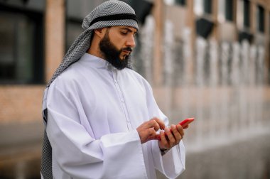 Bağlandı. Elinde akıllı telefon olan Arap bir adam.