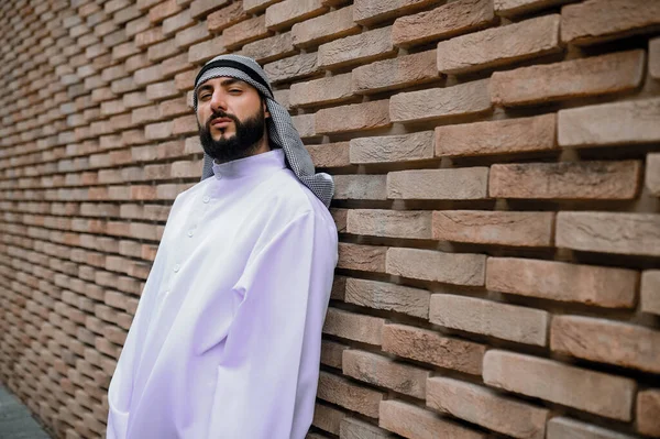 アラビア人だ レンガの壁の近くに立っている伝統的なアラビア語の頭飾りの男 — ストック写真