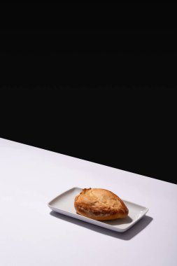 Freshly baked Mexican artisan bread on a white plate on a white table and a black wall in the background, no people