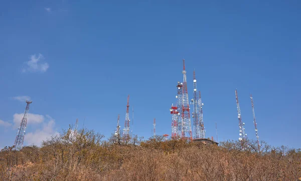 Çöl ormanının ortasındaki bir dağın tepesinde iletişim kuleleri, yaz günü mavi gökyüzü, insanlar, kayalar ve palmiyeler yok.