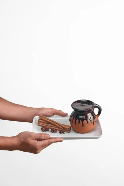 a man holding a white plate with chocolate champurrado, anise and cinnamon, traditional mexican chocolate drink on white background, objects