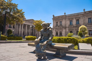 Statue of a man sitting with a girl in front of the theater of La Paz in Plaza del Carmen, the historic center of the city, no people