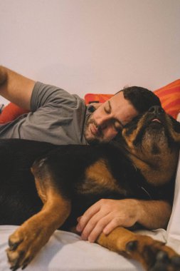 Rottweiler köpeğiyle yatan adam.