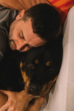 Rottweiler köpeğiyle yatan adam.