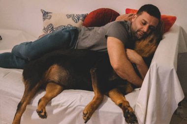 Rottweiler köpeğiyle yatan adam.