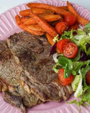 Biftek, kızarmış patates ve salata karışımı.