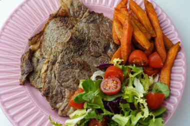 Biftek, kızarmış patates ve salata karışımı.