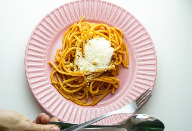 Domates soslu ve parmesan peynirli pembe bir tabak taze spagetti.