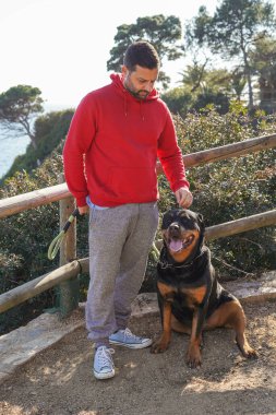 Parkta Rottweiler köpeğiyle oynayan adam