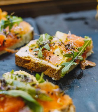 Somon tostu, taze peynir, avokado ve roka.