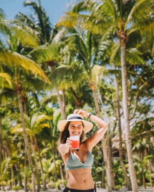 Tropik bir plajda bikinili bir kadın poz veriyor.