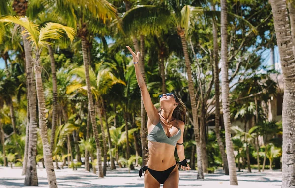 女模特穿着比基尼站在一个有棕榈树的天堂海滩上 — 图库照片