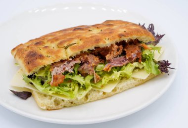 Ciabatta ekmekli sandviç, yanında domuz eti ve sebze.