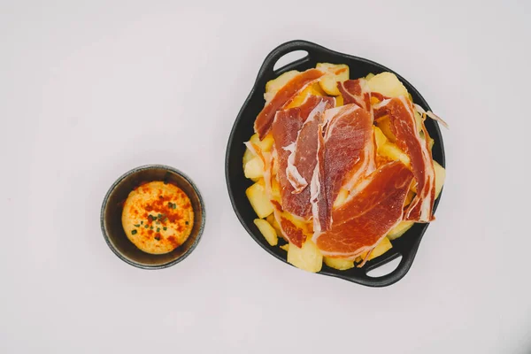 Spanish patatas bravas ration with Iberian cured ham