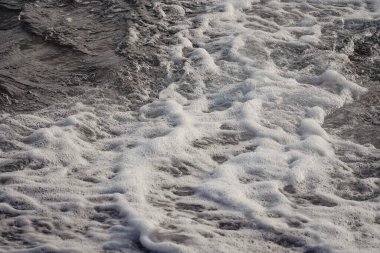Landscape of a beach shore with waves and foam