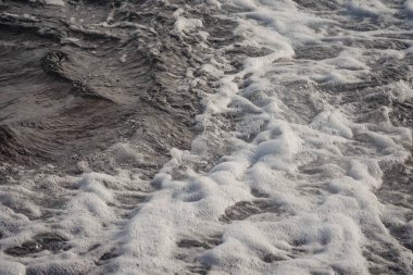Landscape of a beach shore with waves and foam