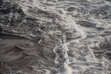 Landscape of a beach shore with waves and foam