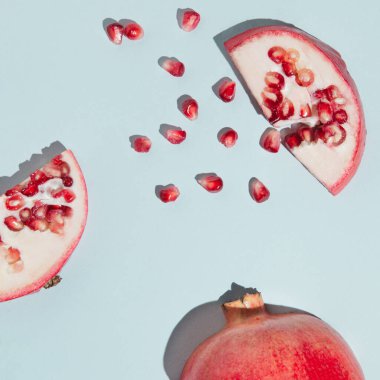 Tohumlar ve nar deseninden yapılmış yaratıcı nar deseni pastel mavi arka planda açılır. Taze meyve minimalizmi kavramı.