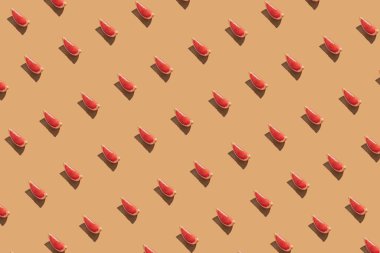 Pastel turuncu arka planda taze kırmızı greyfurt dilimlerinden oluşan yaratıcı desen. En düşük yaz meyve düzeni.