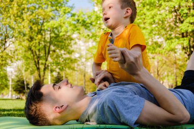 Neşeli iki kardeş parkta çim üzerinde yalan ve gülümseyen komik oyun oynamak