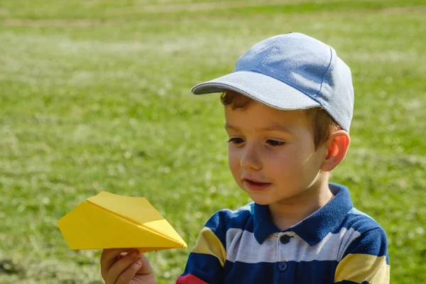 日当たりの良い夏の日に公園で黄色のおもちゃの飛行機と遊ぶ少年 — ストック写真