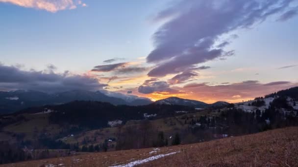 Un coucher de soleil épique avec de belles couleurs chaudes, des nuages colorés mouvants sur les montagnes coiffées — Video
