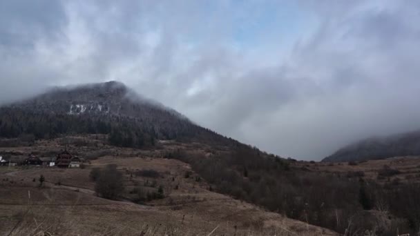 Husté mraky pohybující se kolem skalnatého kopce při západu slunce v zataženém počasí — Stock video