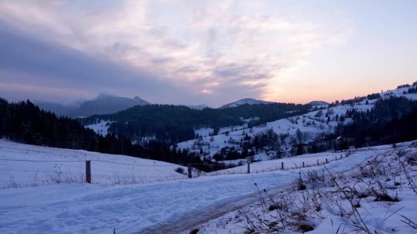 Zimowy śnieżny mroźny krajobraz z płotem, kolorowe ruchome czerwone chmury,, zmierzch nad śnieżnym krajobrazem — Wideo stockowe