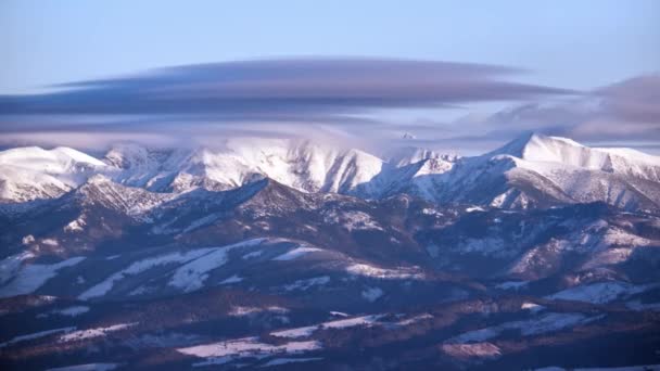 Schneebedeckte Berggipfel. Die Wolken schwappen über die Berggipfel. Winterlandschaft — Stockvideo