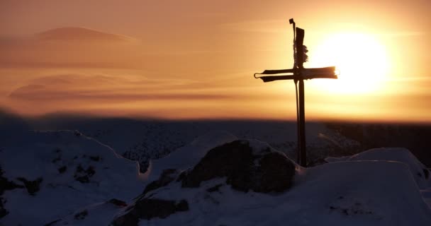 Železo vyrobený křesťanský kříž na vrcholu hory přes zimu. Slunce na oranžové obloze, západ slunce — Stock video