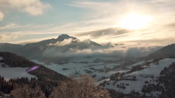 Paysage d'hiver de montagne, le soleil brille à travers les nuages, les nuages débordent sur les collines — Video