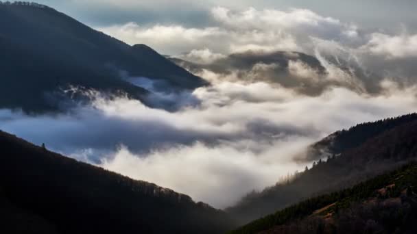 Le nuvole si rovesciano sulle cime delle colline alla luce del sole nascente, atmosfera mistica — Video Stock