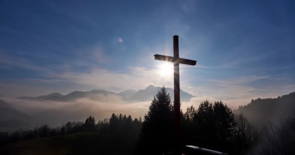 Christian cross in the glow of the sun, mountain landscape above the clouds — Stockvideo