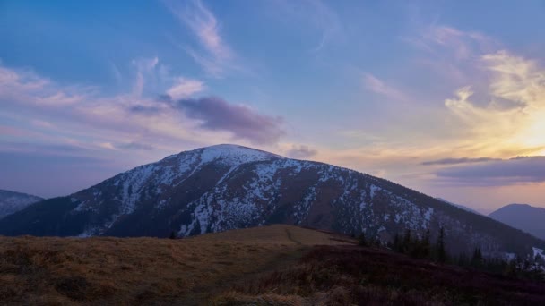 Colorful clouds at sunset, in a spring mountain landscape, melting snow. — Stock video