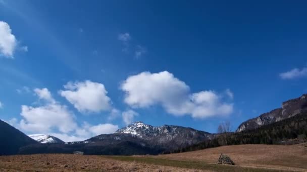 Pastos montañosos en primavera, la última nieve en las crestas montañosas, nubes en el cielo azul en movimiento — Vídeo de stock